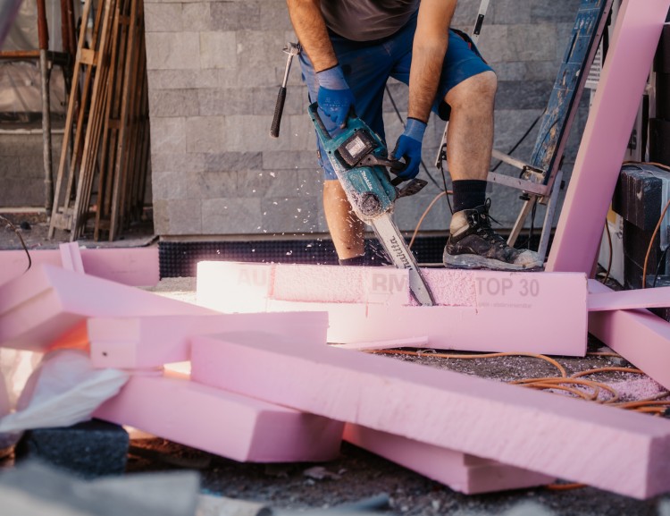Handwerker schneidet Isoliermaterial mit Motorsäge