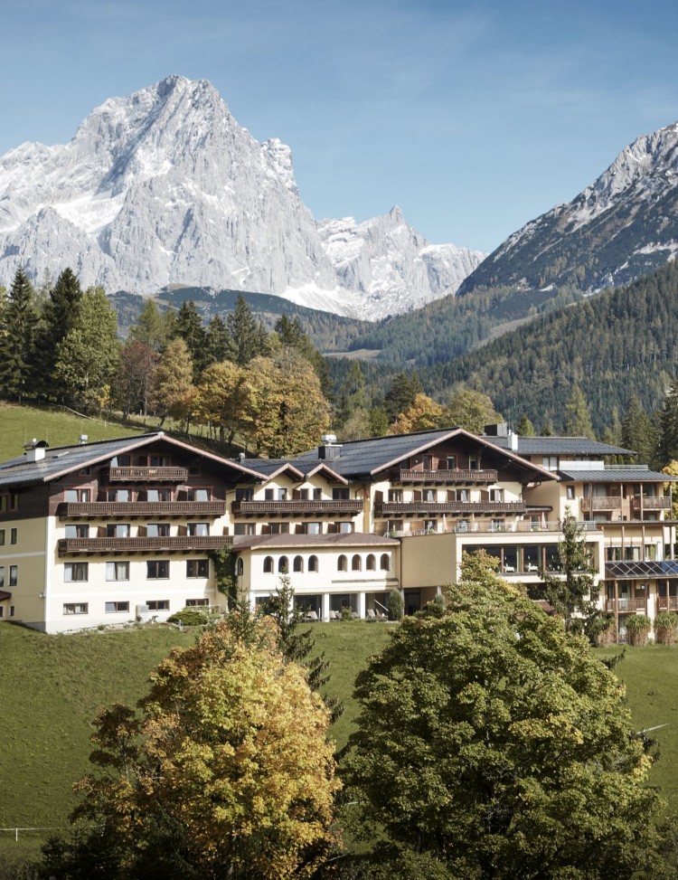 Das Hotel im Sommer - eingebettet zwischen Wiesen, Bäumen und den Bergen © Klaus Bauer
