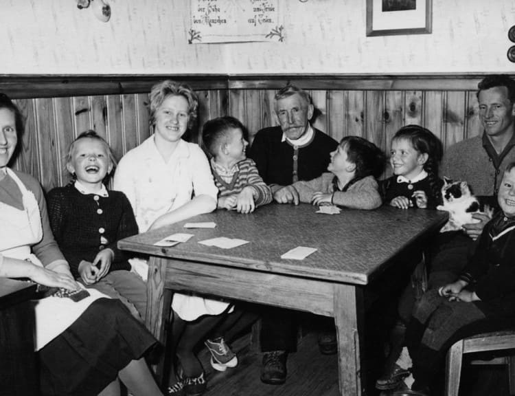 In der Stube sitzt man gerne zusammen. Außen - Eva und Sepp Reiter (mit der Katze am Schoß) und die 4 Kinder rund um den Tisch verteilt.